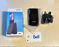 Phone, box, charger and SIM card laid out on table