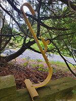 Side view of yellow Acro roof ridge ladder hook showing curved hook, wheel, and clamp