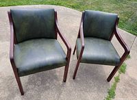 Two matching dark green padded wooden arm chairs