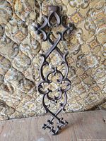 Full view of wrought iron wall plaque against patterned backdrop