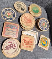 Overview of assorted vintage beer coasters on chair