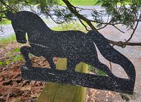 Front view of black painted horse silhouette on wooden rail