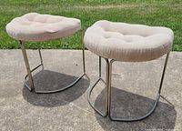 Pair of stools upright on concrete showing seats and chrome bases