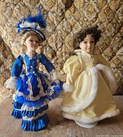 Both porcelain dolls side by side on table