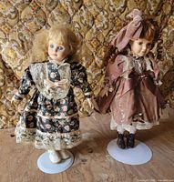 Both porcelain dolls on stands side by side