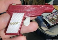 Left side view showing gold 007 logo, red body, white grip