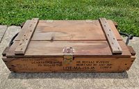Top view of closed wooden ammunition crate showing latch, rope handles, stencilled markings