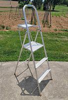 Front angled view of four-step aluminum ladder with handrail and tray