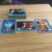 Full stack of E.T. trading cards on table showing three sample fronts
