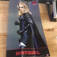 Full view of folded Batgirl poster on wooden surface