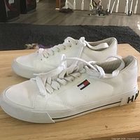 Left profile of white Tommy Hilfiger sneaker on table