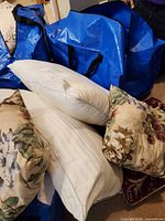 Group of pillows showing white striped standard pillow, floral square pillow, burgundy pillow