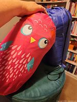 Pink owl print stuff sack held next to blue stuff sack