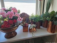 Group view of all copper pieces with artificial florals on shelf