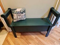 Full view of green storage bench with pillow on seat