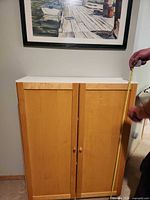 Front view of light wood cabinet under framed picture