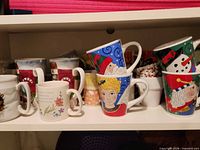 Shelf view showing assorted holiday, floral and novelty mugs