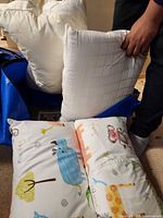 Animal-print and white pillows in blue zip bag