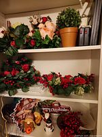 Shelved lot showing artificial floral arrangements, faux potted plant, holiday signs, ceramic snowmen, berry picks