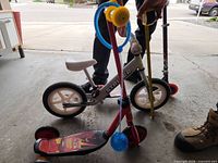 All three ride-on items: Strider bike, Disney 3-wheel scooter with accessories, Razor scooter