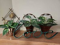 Overall view of teal metal sign and three copper planters with faux plants on shelf