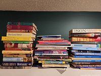 Three stacks of assorted books showing variety of titles and formats