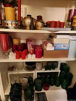 Shelves filled with assorted red, green, gold and ivory candles, glass hurricanes, metal lanterns and LED tealight boxes