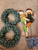 Two wreaths and two scarecrow stakes on floor