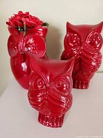 Front view of all three red ceramic owl pieces with flowers