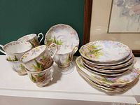 Group of teacups, sugar bowl and stack of saucers/dessert plates
