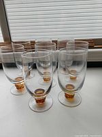 Front view of all eight goblets showing clear bowls and amber stems