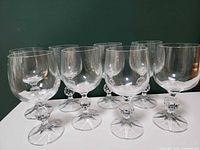 Front angled view showing all eight clear wine glasses with faceted stems