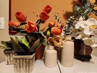 Group shot of three ceramic vases with artificial flowers