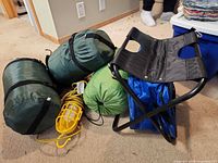Three green sleeping bags, yellow work light, folding chair
