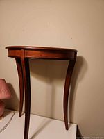 Side view of demilune console table showing curved top, apron and three legs