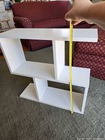 Front view showing two-tier asymmetrical white shelf