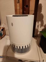 Front view of white cylindrical air purifier with vertical intake vents