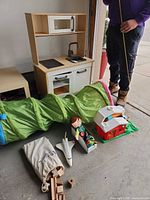 Overall lot showing play kitchen, tunnel, barn house, shuttle, doll, train track bag