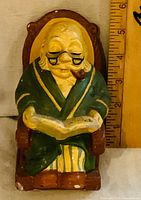 Front view elderly man coin bank showing book and rocker base