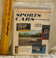Front cover showing full magazine in bag with ruler for scale