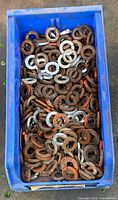 Top view of blue bin filled with steel split lock washers showing mix of rusted and clean pieces