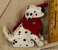 Left side view of wooden Dalmatian figurine beside ruler