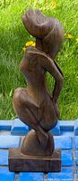 front view of carved wood female figure on base