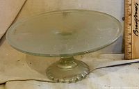 side view of frosted glass cake stand showing pedestal and scalloped base