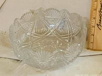 Side view of bowl showing scalloped rim and cut pattern with ruler for scale