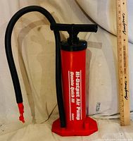 Full view of red Intex air pump with hose beside yardstick for scale