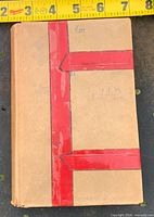 Front view of hardcover book with measuring tape indicating size
