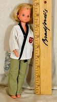 Front view of doll beside ruler showing height and clothing details