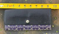 Closed clutch purse beside measuring tape showing length ~7.5 in.