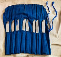 open pouch displaying eight silver knives in individual slots